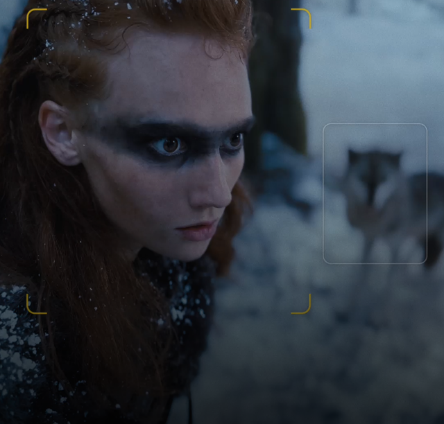Kadr obrazujący działanie Trybu filmowego. Ostrość jest ustawiona na osobę na pierwszym planie, a w tle widać jeszcze dwójkę bohaterów.