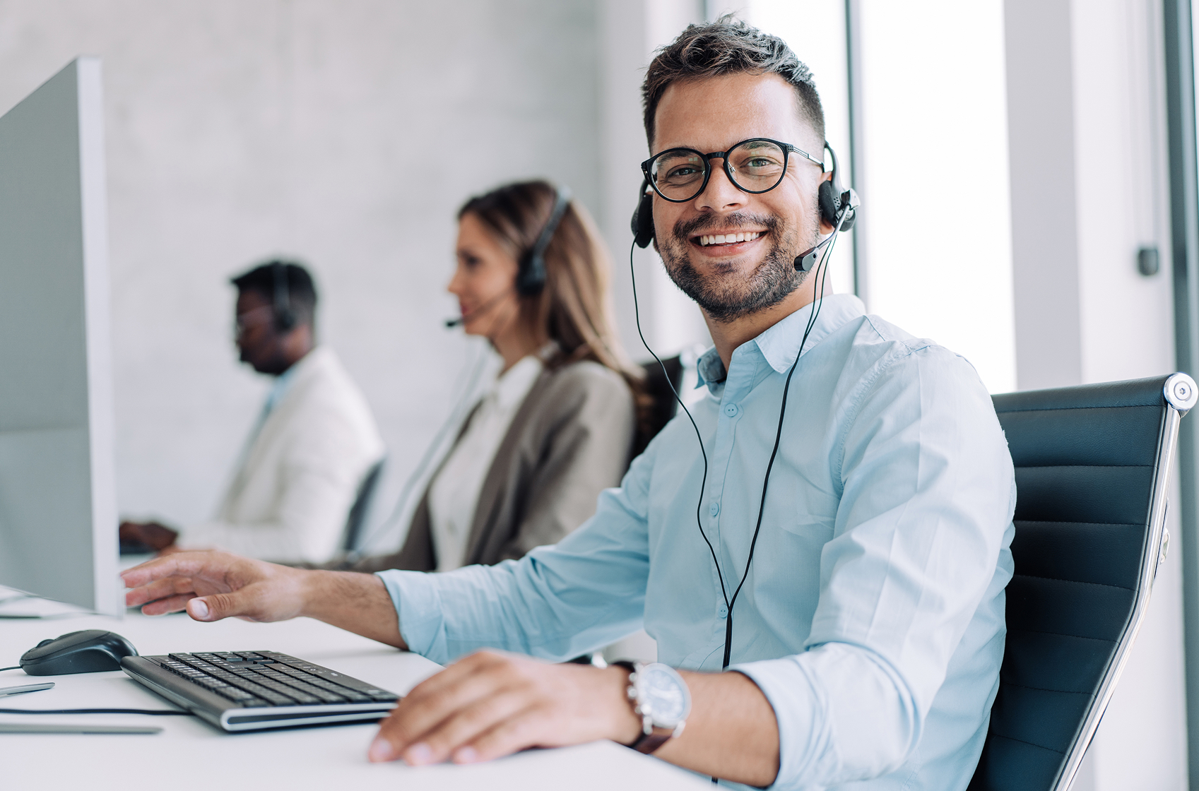 Zdjęcie przedstawia uśmiechającego się mężczyznę w słuchawkach z mikrofonem