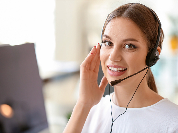 Uśmiechająca się kobieta trzyma kartki papieru. W tle widok wnętrza restauracji.