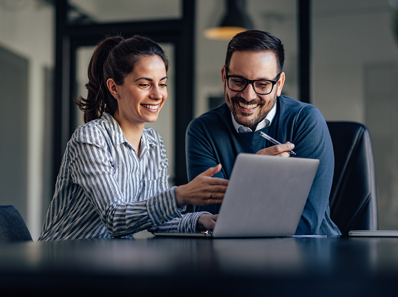 Uśmiechająca się kobieta trzyma kartki papieru. W tle widok wnętrza restauracji.